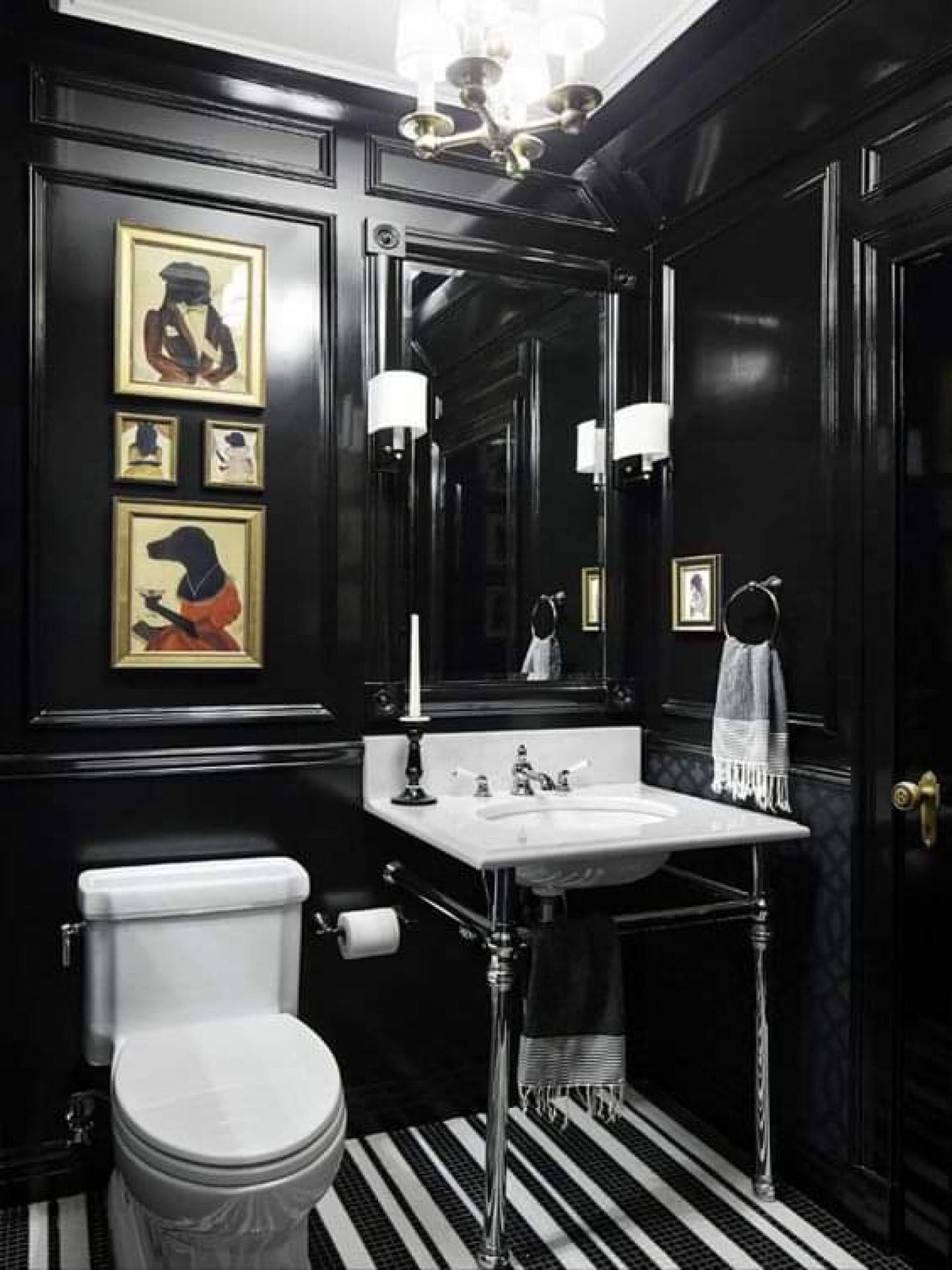 Parlak siyah wainscoting duvar panelleri, mermer konsol lavabo, altın çerçeveli tablolar ve siyah beyaz çizgili zeminli klasik banyo.