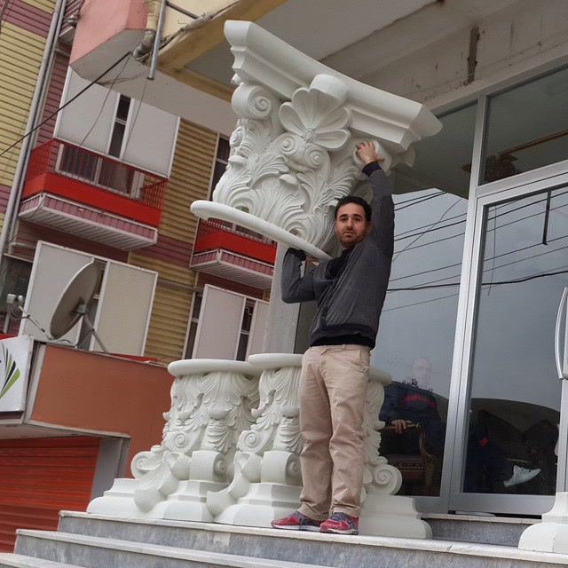 Çayırova'da dükkan önünde ustanın omuzunda taşıdığı büyük oymalı beyaz Korint poliüretan sütun başlığı gösterimi.