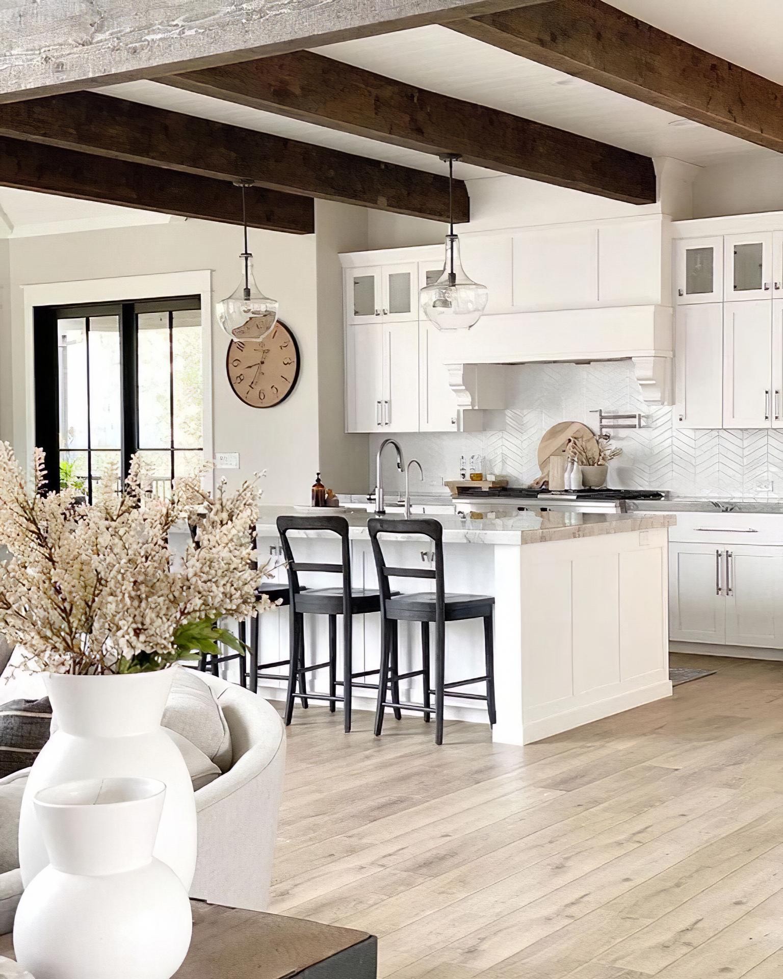 Koyu ahşap tavan kirişli, beyaz adalı ve siyah bar tabureli modern farmhouse mutfak dekorasyonu