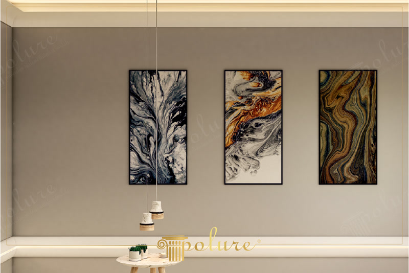Gizli LED aydınlatmalı tavan kartonpiyeri, duvarda asılı üç adet soyut mermer tablo ve modern sarkıt lambalar içeren minimalist iç mekan tasarımı.