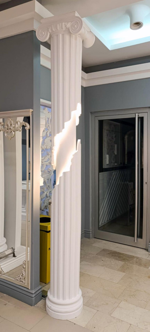 Showroom girişinde aydınlatmalı yivli poliüretan İyon sütun, gümüş oymalı ayna çerçevesi sövesi ve cam kapı.