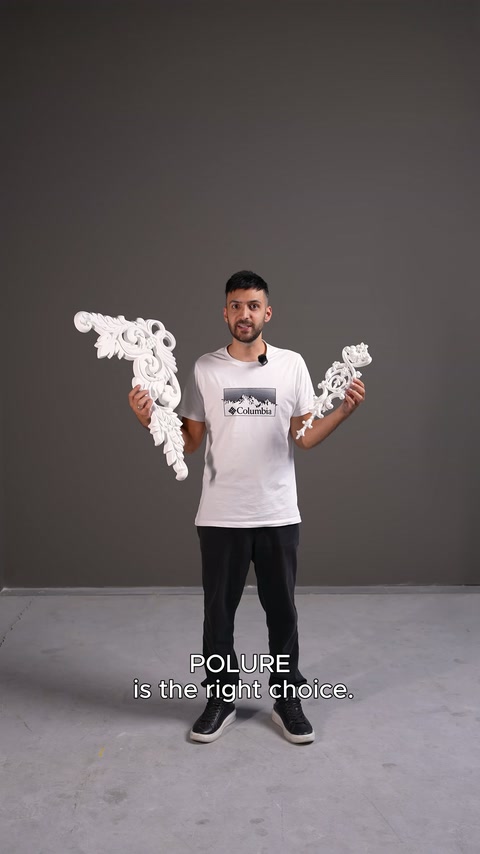 Sunucu stüdyoda yaprak bezemeli iki dekoratif köşe parçasını elinde tutuyor