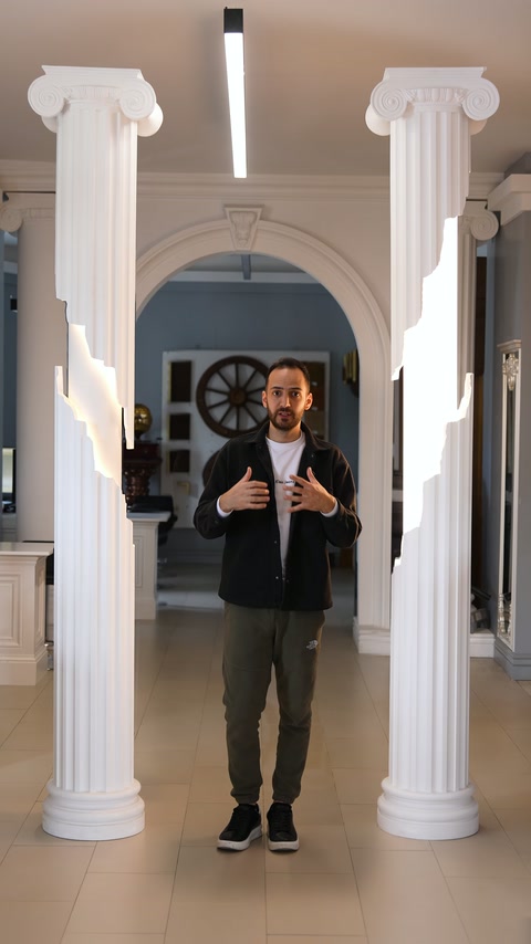 Kemerli showroom alanında iki ışıklı sütun ve sunucu birlikte görülüyor
