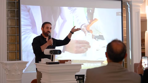 Konuşmacı perde önünde ürün biçimlerini eliyle açıklıyor
