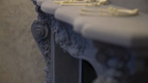 Şömine çevresindeki kıvrımlı kabartma ve bezemeler yakından gösteriliyor