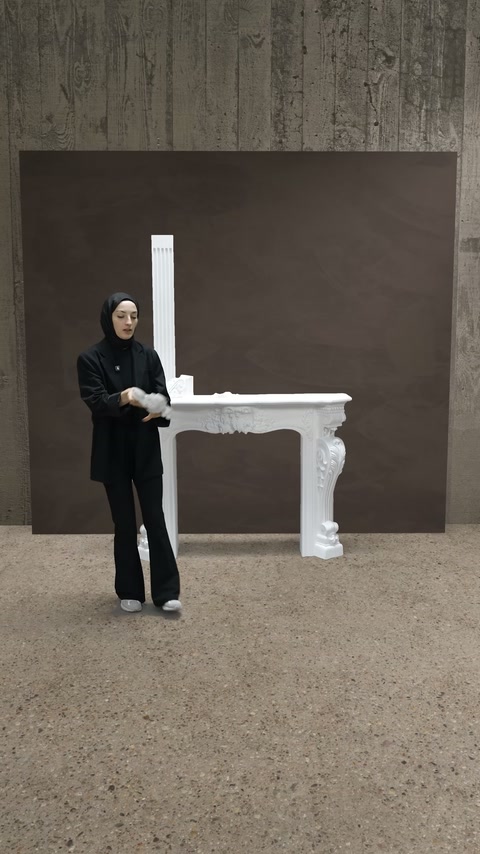 Kabartmalı parça, şömine rafı önünde iki elle inceleniyor