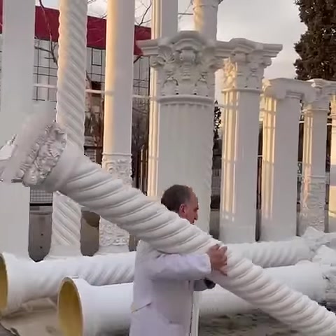 Usta, uzun burmalı sütun parçasını iki eliyle taşıyor