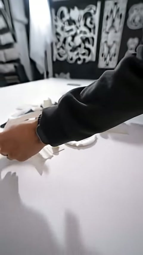 Görevli beyaz masadaki minyatür süsleme parçalarını düzenlemeye başlıyor.
