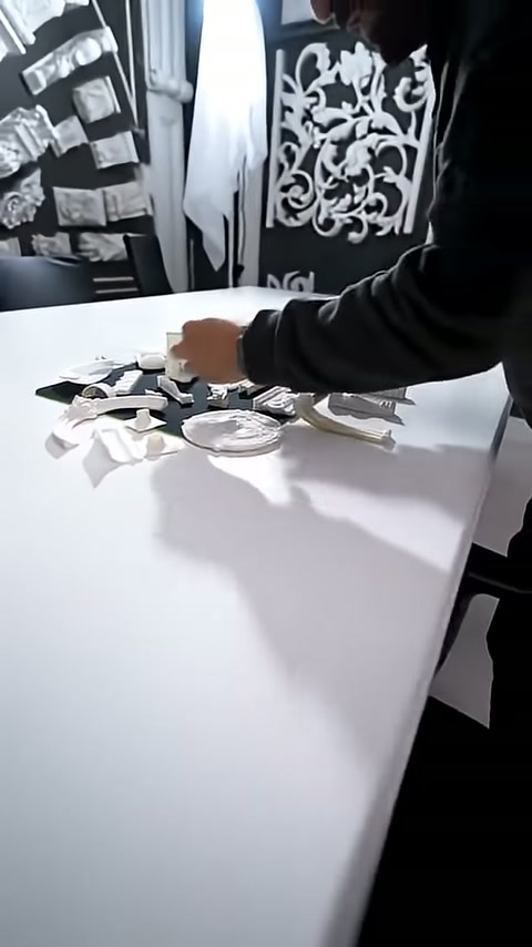 Küçük beyaz mimari süsler sergileme masasında yan yana diziliyor.