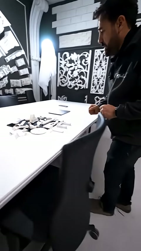 Stant görevlisi masadaki küçük beyaz dekorasyon parçalarını inceliyor.