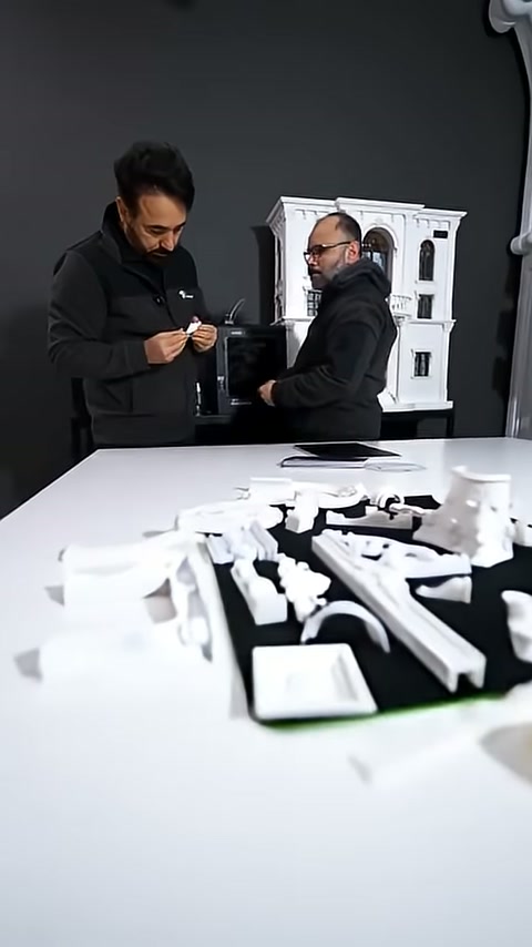 İki görevli maket önünde küçük ürünler hakkında görüşüyor.