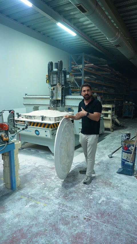 Görevli, CNC bölümünde dik duran işlemeli tavan göbeklerini açıklıyor.