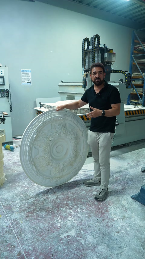 Görevli, büyük yuvarlak göbeği CNC makinesinin yanında dik tutuyor.