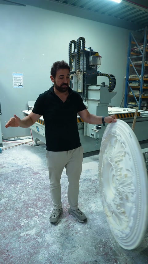 Görevli, işlemeli ve sade tavan göbeklerinin tasarımlarını birlikte tanıtıyor.