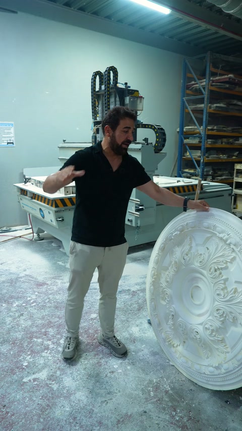 Sunucu, CNC tezgâhının yanındaki kabartmalı yuvarlak göbeği işaret ediyor.
