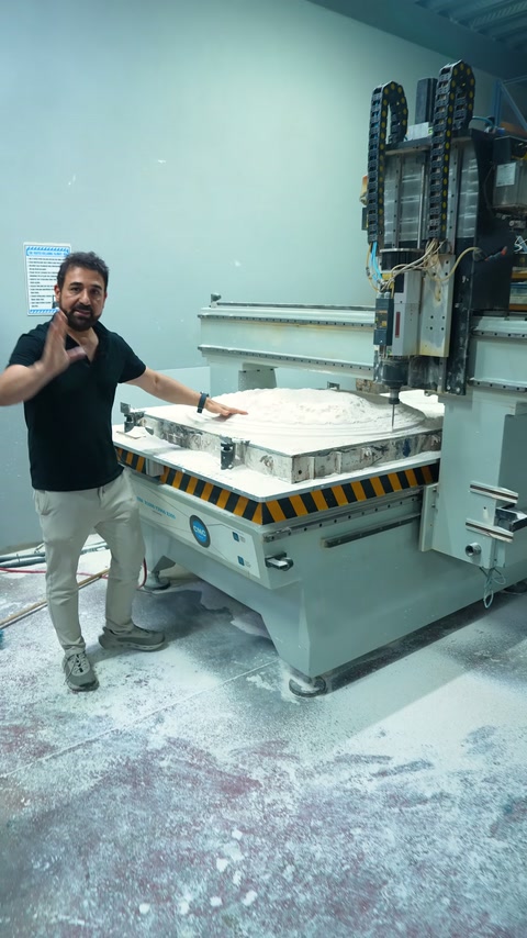 Sunucu, CNC makinesi önünde üretim aşamalarını el hareketleriyle anlatıyor.