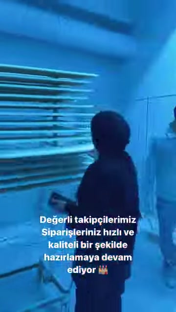 Çalışan, raflardaki uzun beyaz profillerin önünde açıklama yapıyor.