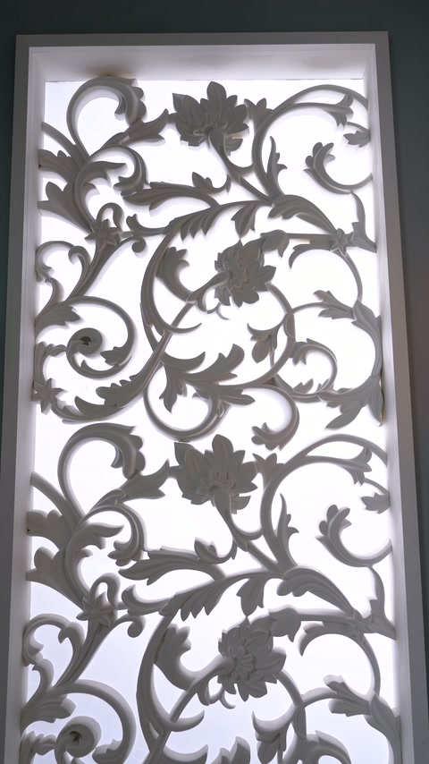 Dikey panel yüzeyindeki çiçek rozetleri ve kıvrımlı yapraklar birlikte görülüyor