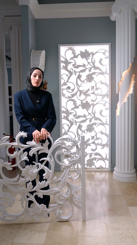 Görevli, dekoratif panel örneğinin arkasında sütunlar ve apliklerle birlikte duruyor