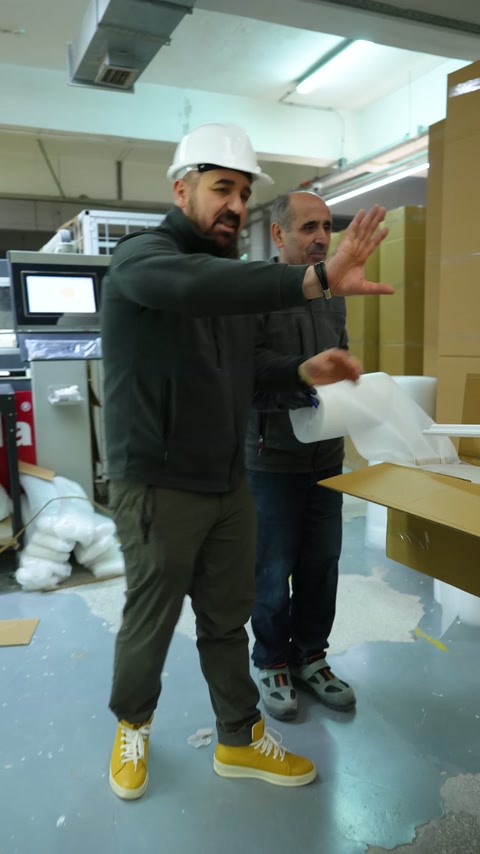 Baretli görevli, profil paketleme istasyonundaki işlemi eliyle açıklıyor.