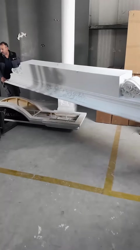 Uzun işlemeli üst taç parçası iki görevli tarafından taşınıyor.