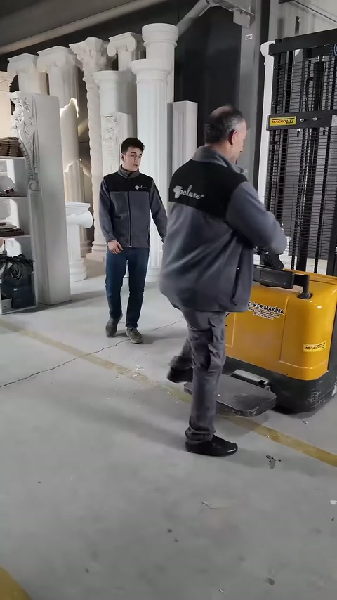 Operatör, kaldırma aracını sergilenen sütunların önünde geri çeviriyor.