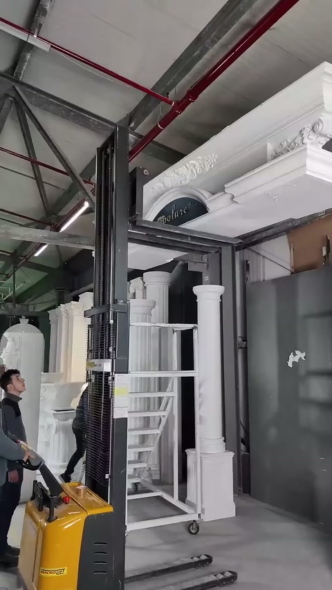 İşlemeli taç elemanı, iki beyaz sütunun üzerinde sergileniyor.