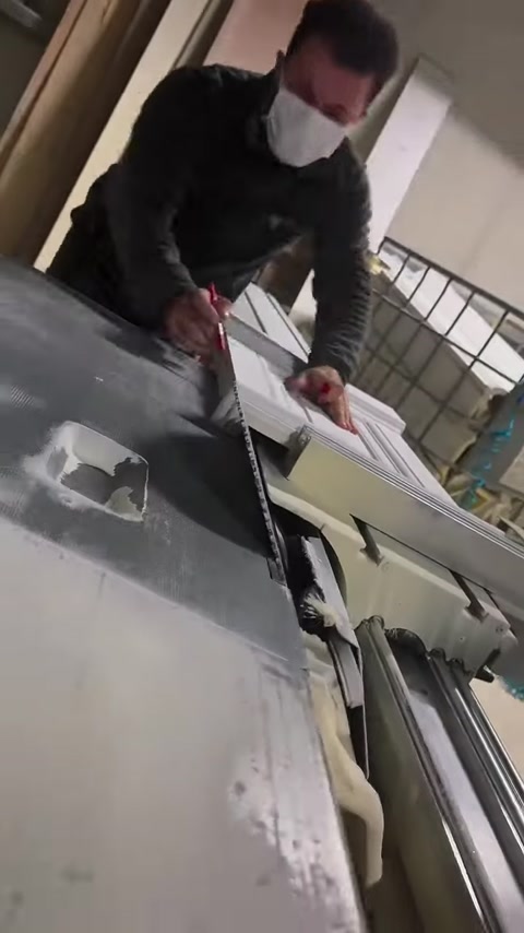 Dekoratif yüzeyli beyaz söve tezgâhlı testereyle kesiliyor.