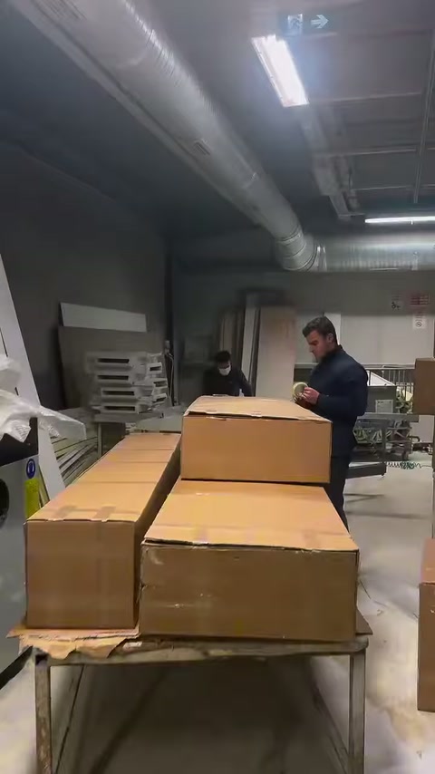 Çalışan, çalışma masasındaki açık karton kutuların arkasında duruyor.