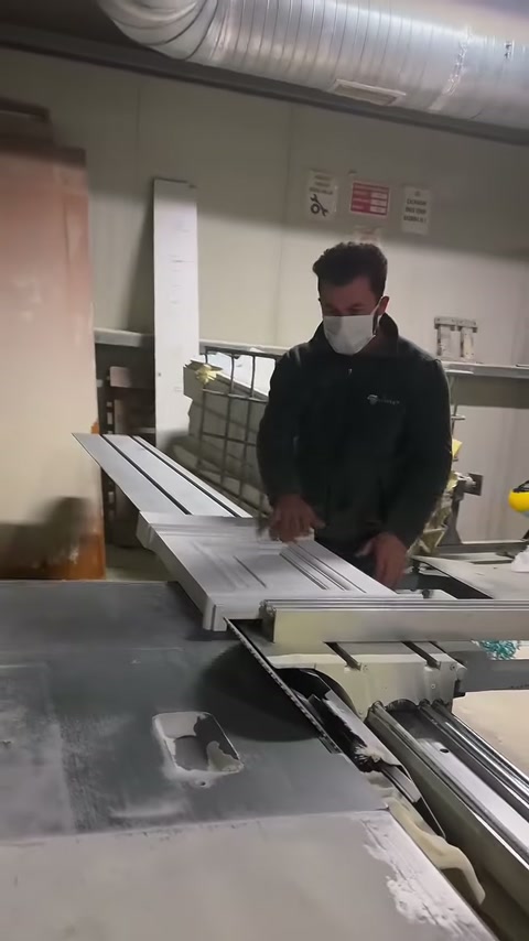 Çalışan, uzun parçaların kenarlarını makine kılavuzuna dikkatle dayıyor.