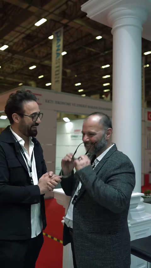 Sütunlu stand önünde ürün tanıtımı ve karşılıklı görüşme sürüyor