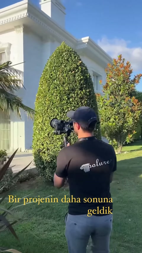 Bahçe çekiminde beyaz villanın balkon korkulukları, kolonları ve kornişleri öne çıkıyor.