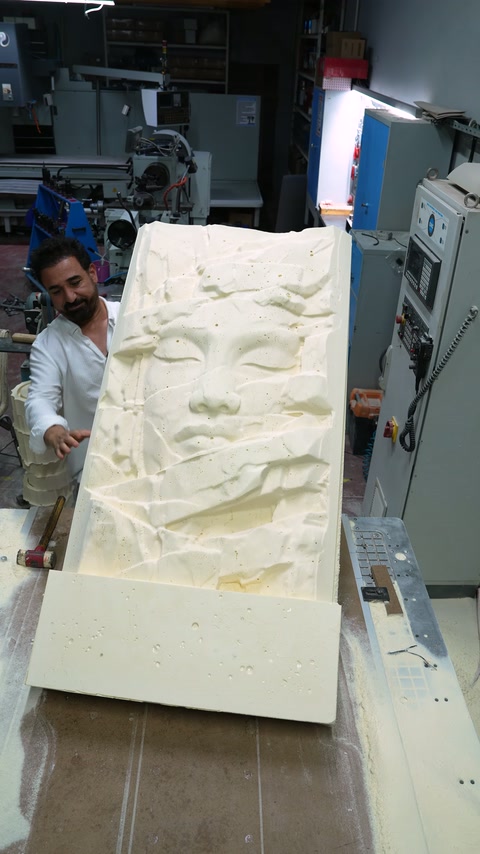 Dikey kaldırılan panoda yüz figürü ve geometrik parçalar görülüyor.