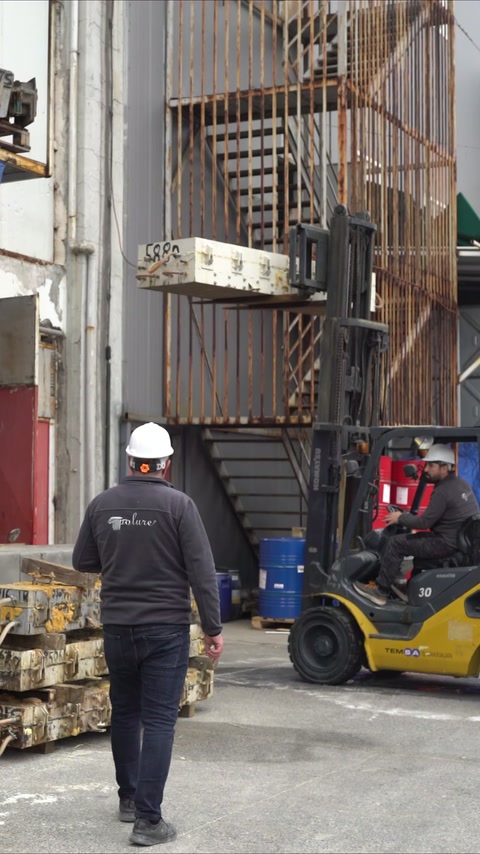 Çalışan, dış depodaki profil raflarının yanında forklift operasyonunu izliyor