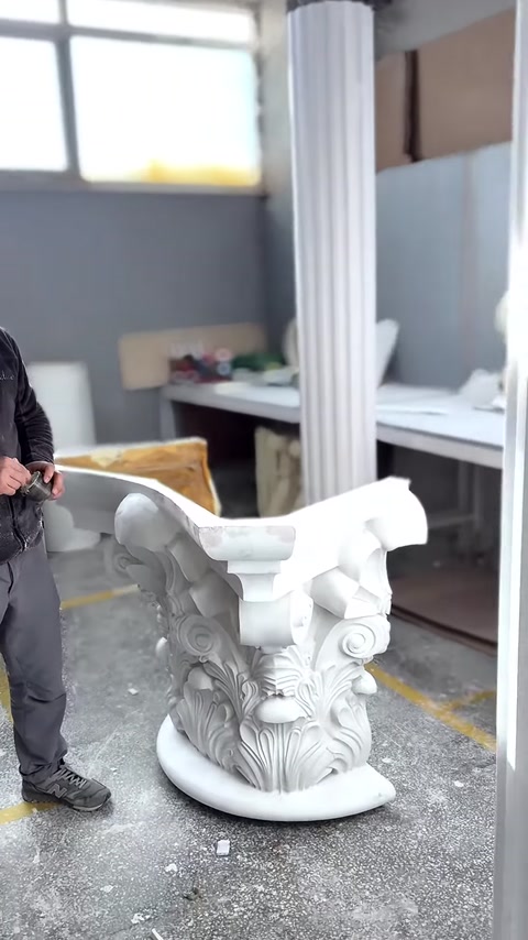 Beyaz Korint sütun başlığı, volütleri ve köşe çıkıntılarıyla sergileniyor.