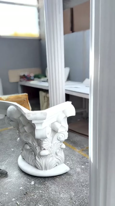 Beyaz Korint başlığı, yuvarlak tabanı üzerinde tek başına sergileniyor.