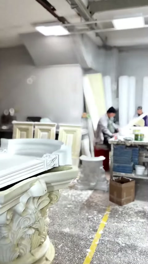 Geniş atölyede Korint başlıkları, levhalar ve çalışma masaları görülüyor.