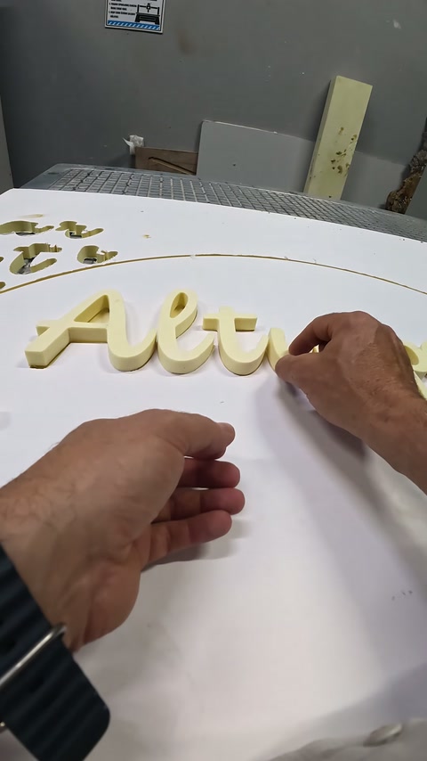 Kabartma yazı parçaları, beyaz pano üzerinde elle hizalanarak yerleştiriliyor.