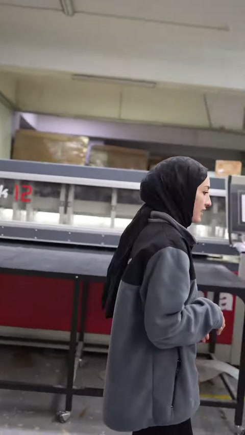 Sunucu, üretim görevlisiyle paketleme makinesi yanında görüşüyor