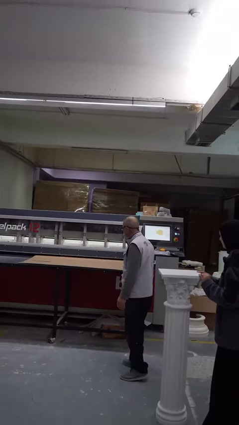 Operatör, sütun parçası yanında paketleme makinesini çalışmaya hazırlıyor