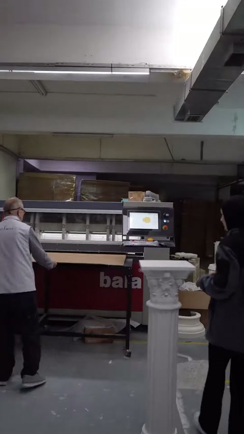 Görevli, dik duran dekoratif sütunun yanında makineyi kontrol ediyor