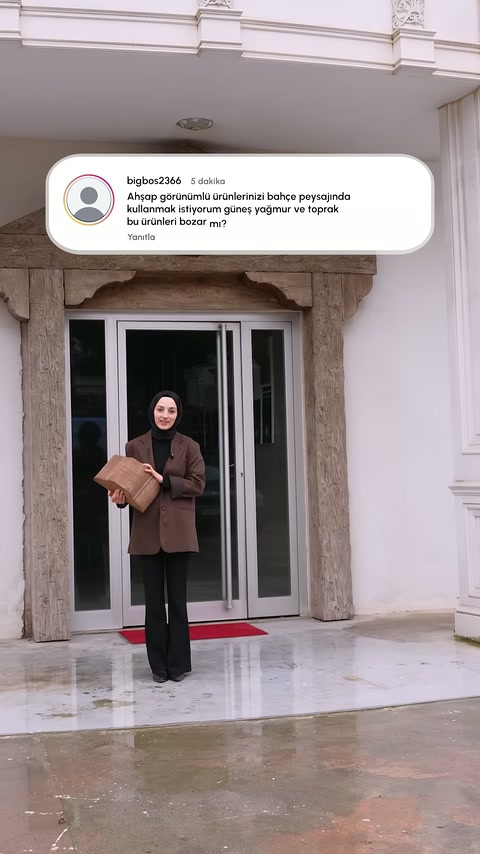 Sunucu bina girişinde elinde kraft kağıda sarılı paket tutuyor