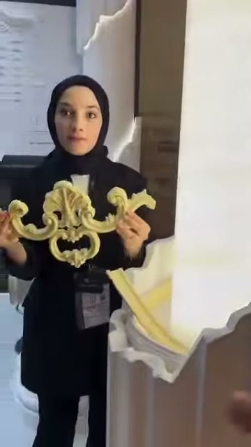 Kıvrımlı bezeme parçası, beyaz dekoratif sütunun önünde tanıtılıyor