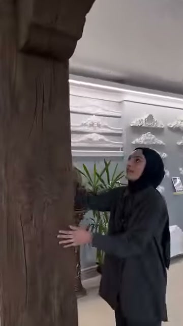 Görevli kalın dekoratif direğin yüzey kaplamasını eliyle gösteriyor