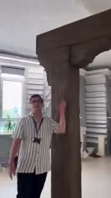 Çizgili gömlekli görevli dikey kütük modelinin yanında sunuma başlıyor