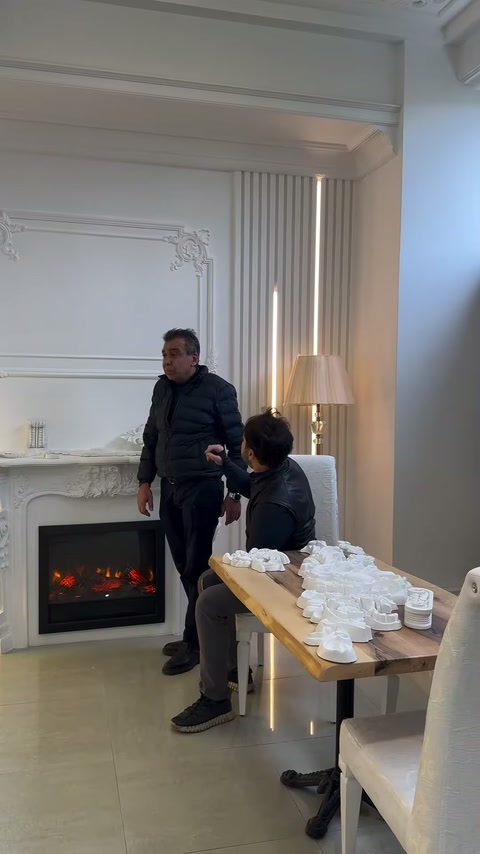 Şömine çevresi bulunan panelli odada iki kişi ürünleri değerlendiriyor