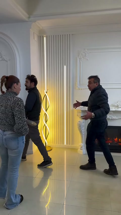 Üç kişi, aydınlatmalı dikey çıtalar önünde ürün detaylarını değerlendiriyor
