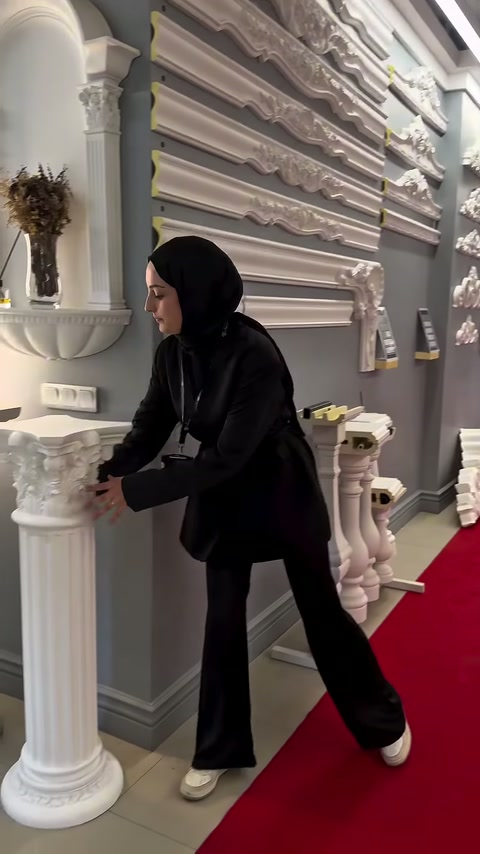 Tanıtıcı, uzun ve ince sütun parçasını iki eliyle kavrıyor.