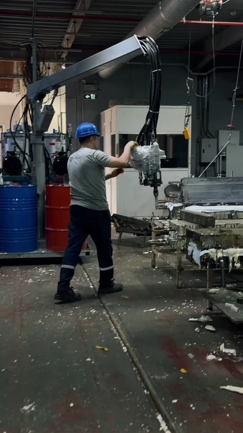 Çalışan, hammadde varillerinin yanındaki döküm ekipmanını kullanıyor
