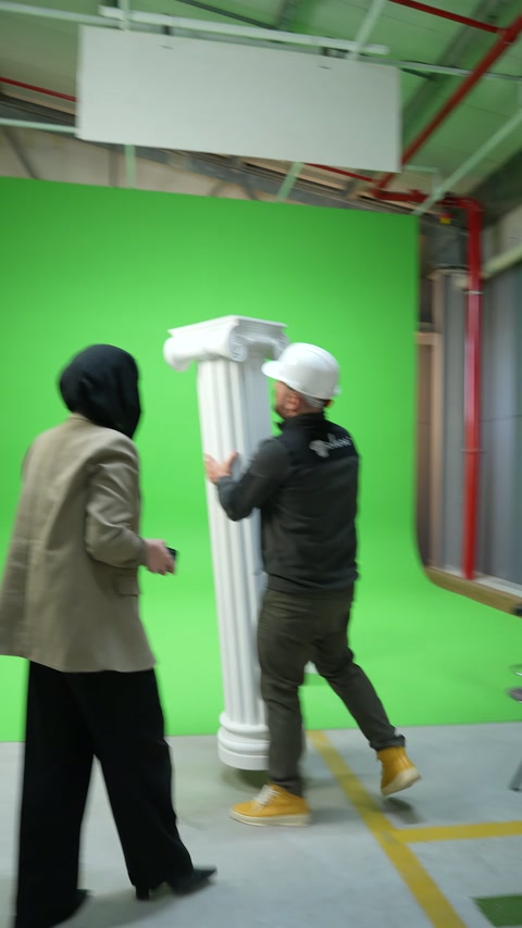 İkili yeşil fon önünde duran yivli sütunu birlikte inceliyor